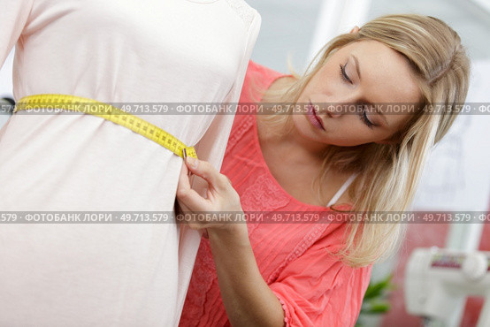 young tailor measuring the mannequin waistline. Стоковое фото, агентство Ingram Publishing / Фотобанк Лори