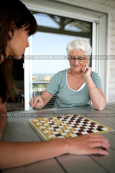 Young woman and senior woman playing checkers. Стоковое фото, агентство Ingram Publishing / Фотобанк Лори