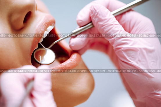 Young woman at the dentist’s chair during a dental procedure. Overview of dental caries prevention. Стоковое фото, агентство Ingram Publishing / Фотобанк Лори