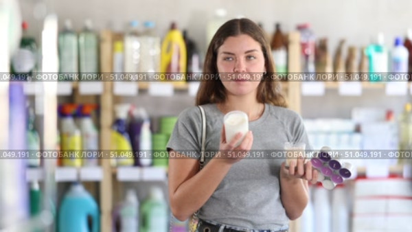 Young woman choosing a set of scented paraffin candles and a soy wax candle. Brunette woman buys candles for the comfort of her home. Стоковое видео, видеограф Яков Филимонов / Фотобанк Лори