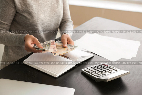 Young woman counting money while sitting at table, closeup. Стоковое фото, фотограф Pixel_shot / Фотобанк Лори