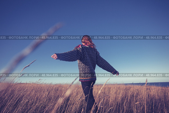 Young woman dancing and spinning around in a field at sunset. Стоковое фото, агентство Ingram Publishing / Фотобанк Лори