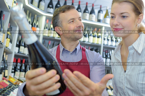 young woman deciding what wine to buy in supermarket. Стоковое фото, агентство Ingram Publishing / Фотобанк Лори