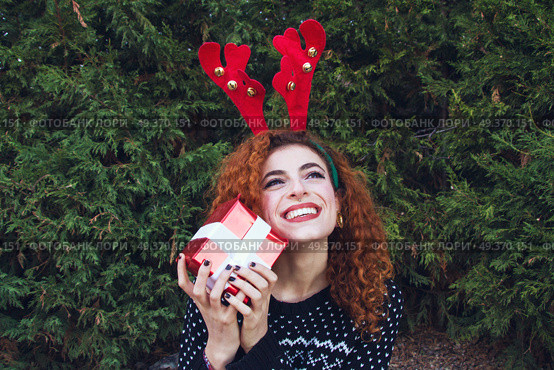 Young woman holding a christmas gift . Стоковое фото, агентство Ingram Publishing / Фотобанк Лори
