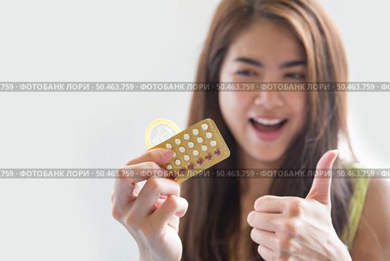Young woman holding condom and contraceptive pills prevent pregnancy. Стоковое фото, агентство Ingram Publishing / Фотобанк Лори