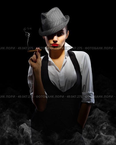 Young woman in manly style with cigar on smoky background. Стоковое фото, агентство Ingram Publishing / Фотобанк Лори