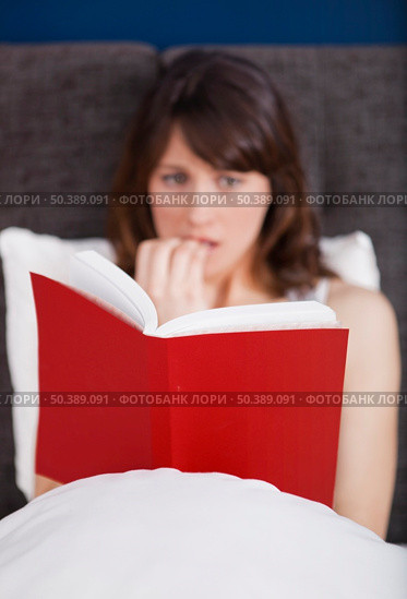 Young woman reading a terror storie with a terrified expression. Стоковое фото, агентство Ingram Publishing / Фотобанк Лори