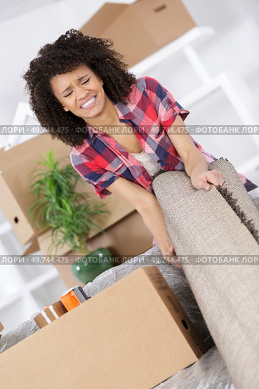young woman suffering from backache while moving carpet. Стоковое фото, агентство Ingram Publishing / Фотобанк Лори