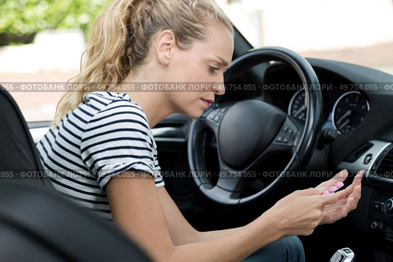 young woman taking pill while driving. Стоковое фото, агентство Ingram Publishing / Фотобанк Лори