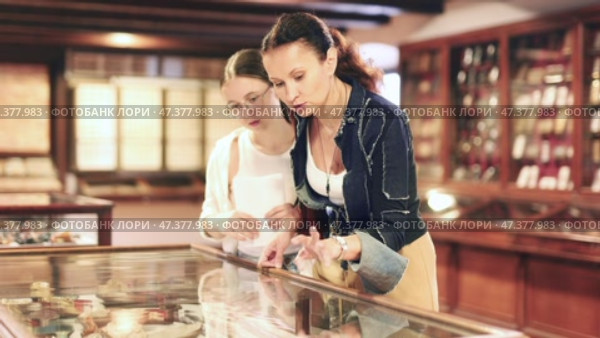 Young woman with teen daughter visitors stands near horizontal glass display case. Стоковое видео, видеограф Яков Филимонов / Фотобанк Лори