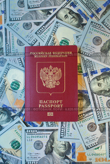 Заграничный паспорт гражданина Российской Федерации на фоне 100-долларовых купюр. Стоковое фото, фотограф Александр Тарасенков / Фотобанк Лори