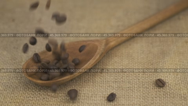 Замедленная съемка. Кофейные зерна сыплются в деревянную ложку, лежащую на мешковине. Горка зерен в ложке. Концепция изобилия продуктов. Стоковое видео, видеограф Александр Собко / Фотобанк Лори