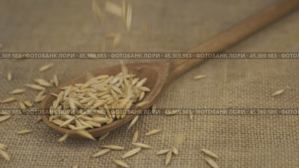 Замедленная съемка. Овсяные зернышки сыплются в деревянную ложку, лежащую на мешковине. Горка зерен в ложке. Концепция изобилия продуктов. Стоковое видео, видеограф Александр Собко / Фотобанк Лори
