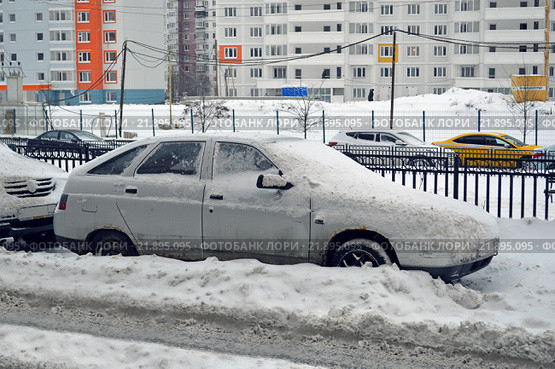 Занесенный снегом старый автомобиль ВАЗ-2112 стоит во дворе дома (2016 год). Редакционное фото, фотограф Александр Замараев / Фотобанк Лори