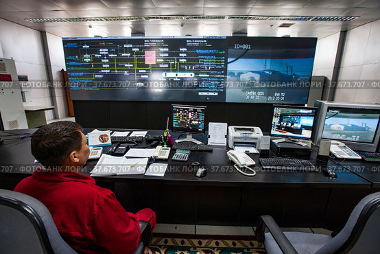 Zhanazhol, Aktobe region, Kazakhstan - May 04 2012: Oil refinery plant. Operational control center (control room). Operator in red work wear monitoring process. CNPC company. Редакционное фото, фотограф Alexey Rezvykh / Фотобанк Лори