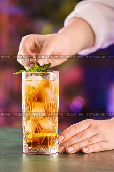Женщина-бармен кладет мяту в стакан вкусного коктейля Cuba Libre на стол в баре. Стоковое фото, фотограф Pixel_shot / Фотобанк Лори