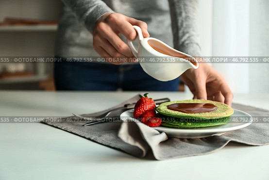 Женщина наливает соус на вкусные зеленые блины. Стоковое фото, фотограф Pixel_shot / Фотобанк Лори