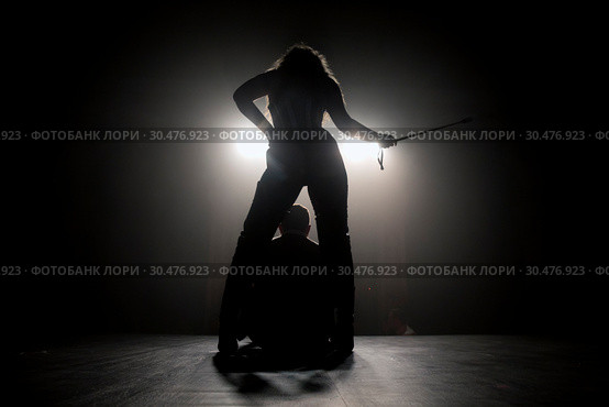 Женщина с плеткой стоит над мужчиной на сцене. Стоковое фото, фотограф Николай Винокуров / Фотобанк Лори