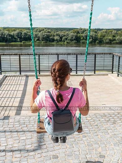 Женщина в футболке качается на качелях на набережной реки. Стоковое фото, фотограф Константин Григорьев / Фотобанк Лори