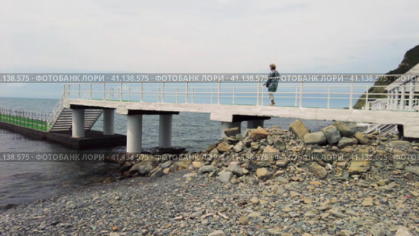 Женщины гуляют по пирсу уходящего в Чёрное море.  Women walk along the pier stretching into the Black Sea. (2023 год). Стоковое видео, видеограф Станислав Типляшин / Фотобанк Лори