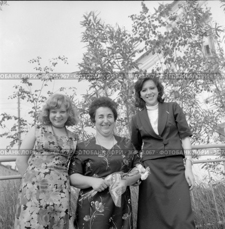 Женщины у здания учебного заведения, фотопортрет студенток рядом с преподавателем, они позируют стоя возле небольших деревьев, девушки с учительницей, Якутия, 1977 год. Редакционное фото, фотограф Варфоломей Тетерин / Фотобанк Лори