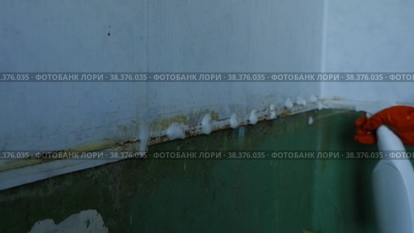 Женская рука крупным планом в оранжевой резиновой перчатке распыляет моющее средство на пластиковую кухонную поверхность.  Работа по дому. Стоковое видео, видеограф Гребенев Пётр / Фотобанк Лори