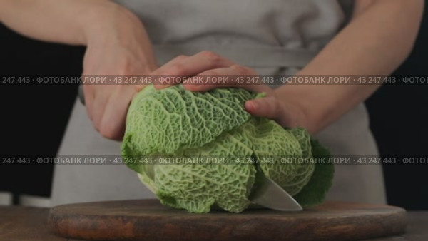 Женские руки берут нож и режут кочан савойской капусты пополам на деревянной разделочной доске. Замедленное движение. Стоковое видео, видеограф Светлана Ельцова / Фотобанк Лори
