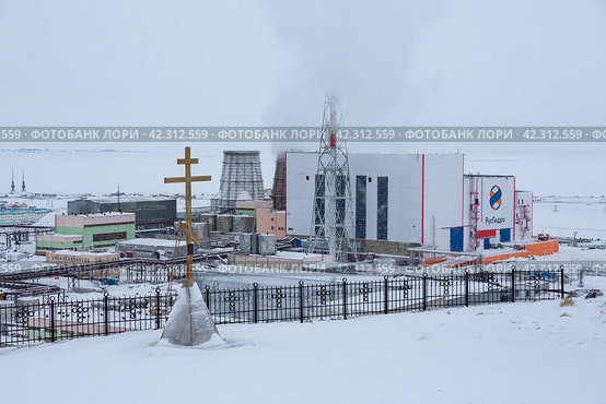 Зимний вид на ТЭЦ и поклонный крест на смотровой площадке. На здании электростанции размещен логотип компании «РусГидро». Анадырь, Чукотка, Россия. Редакционное фото, фотограф Андрей Степанов / Фотобанк Лори